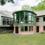 A large green house with a brick wall.