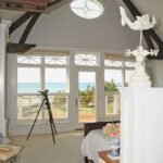 A room with a view of the ocean and a bird statue.