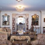 A living room with couches, tables and mirrors.