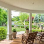 A porch with two rocking chairs and trees