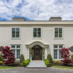 A large white house with a driveway and trees.