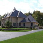 A large house with a driveway and lawn.