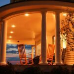 A porch with two rocking chairs and a tree.