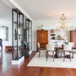 A dining room with a table and chairs, a chandelier and a cabinet.