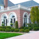 A large brick house with a lawn and bushes.