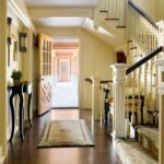 A hallway with stairs and a rug on the floor.