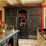 A kitchen with black cabinets and marble counter tops.