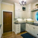 A kitchen with white cabinets and black counter tops.