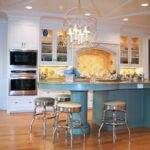 A kitchen with a blue island and white cabinets.