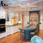 A kitchen with white cabinets and blue island.