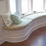 A curved window seat with pillows and storage.