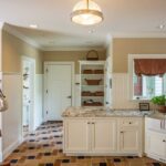 A kitchen with white cabinets and black and white tile floor.