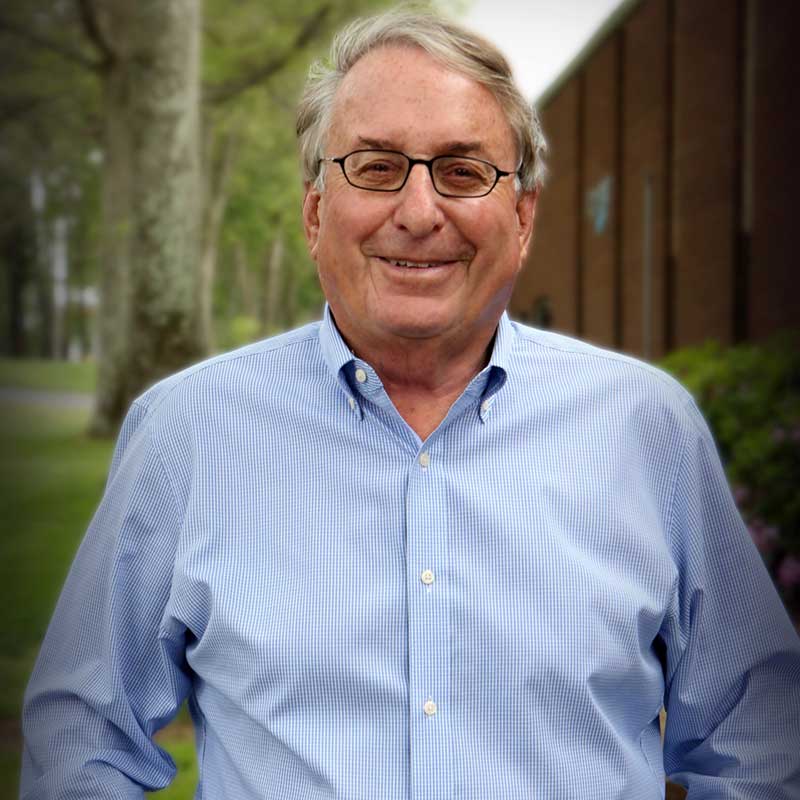 A man in glasses and blue shirt standing outside.