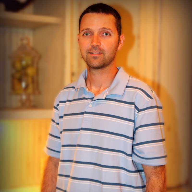 A man in striped shirt standing next to a wall.