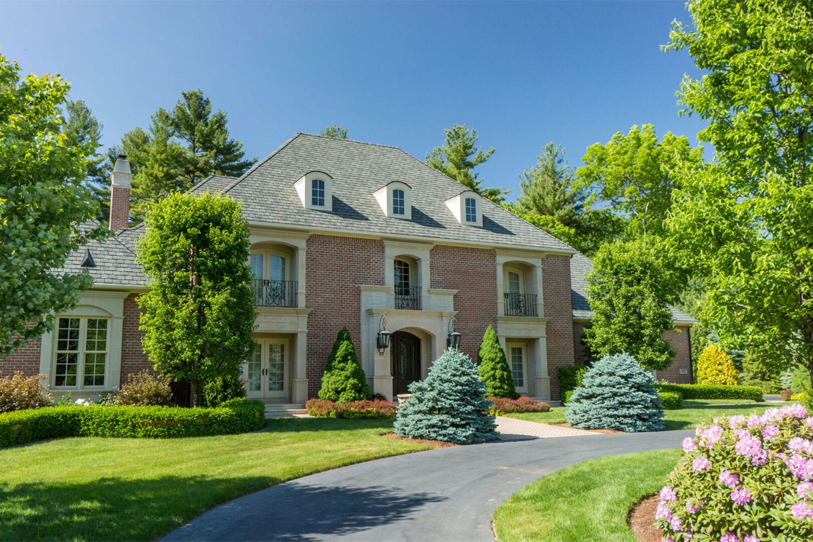 A large brick house with trees in the front yard.