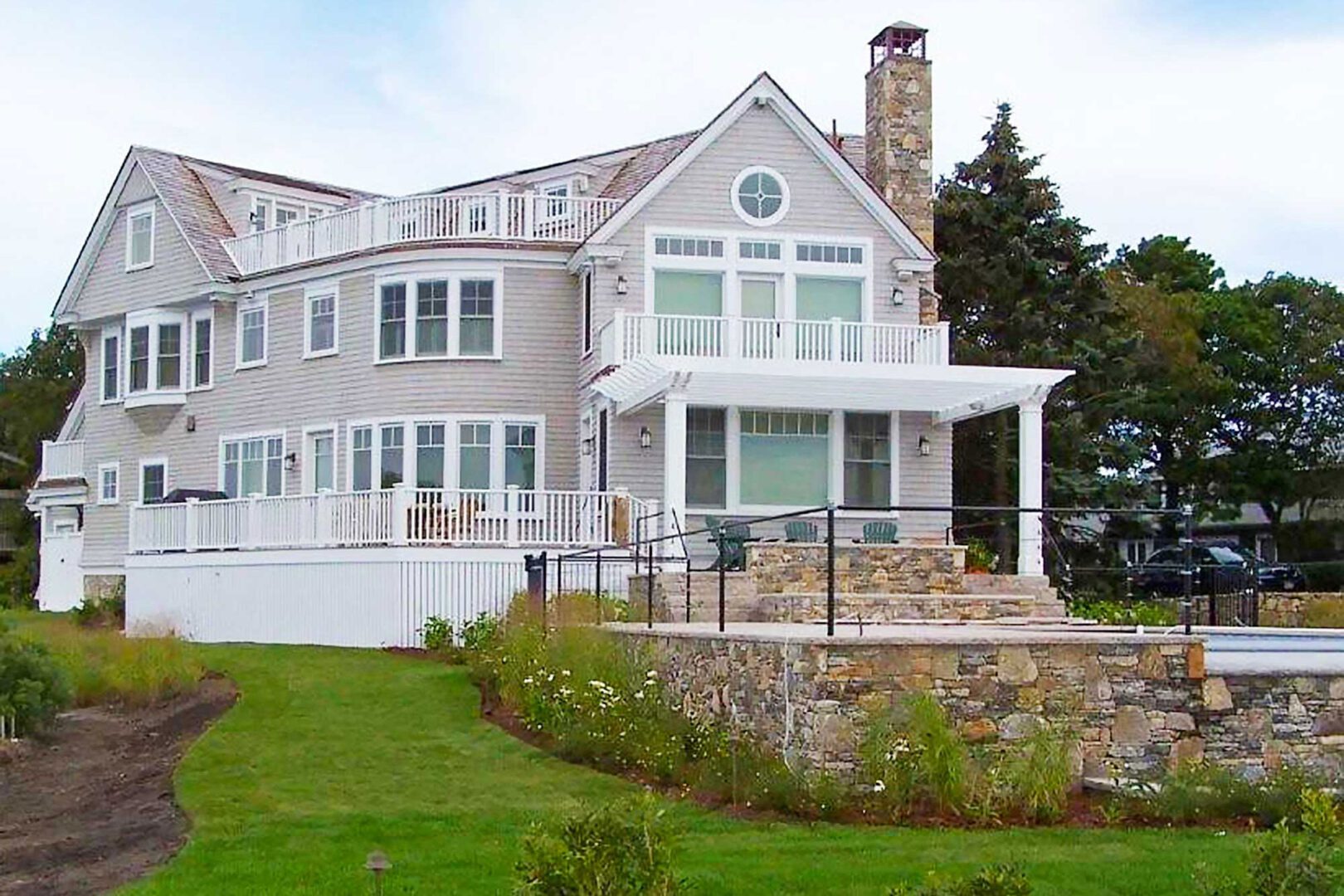 A large white house with a stone wall and green lawn.